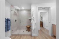 Elegant modern bathroom with a glass-enclosed shower, wooden stool, and soft lighting for a relaxing atmosphere.