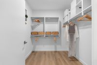 Elegantly designed walk-in closet featuring ample shelving, wooden hangers, and stylish storage baskets.