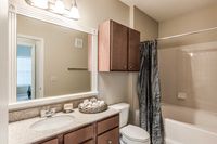 Apartment bathroom with vanity and wood-tone cabinetry at Bennett Baytown