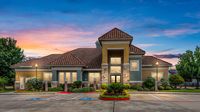 Apartment clubhouse exterior with landscaped entrance at sunset