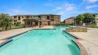 Apartment swimming pool surrounded by lounge seating and landscaping