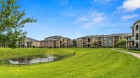 Apartment community green space with walking paths, pond, and residential buildings