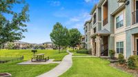 Landscaped walking path beside apartment buildings with picnic area and green space