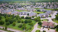 Aerial view of apartment community buildings, green space, and parking