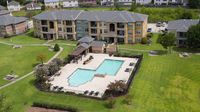Aerial view of community swimming pool surrounded by apartment homes and green space