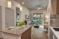 Kitchen island with granite counter, pendant lights and living room with balcony door
