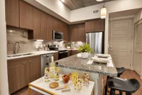 Kitchen with granite island, barstools, wood cabinets and stainless refrigerator