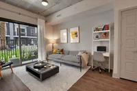 Living room with sofa, coffee table, desk nook and sliding glass door