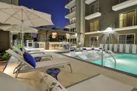 Pool with lounge chairs, umbrellas and mid-rise building at dusk, Houston, TX