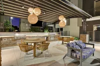 Outdoor kitchen with grills, pendant lights and patio dining under pergola