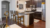 Modern kitchen featuring sleek stainless steel appliances, rich dark wood cabinets, and a stylish granite countertop with bar seating.