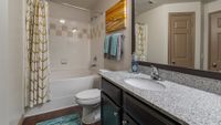 Elegant bathroom showcasing a sleek granite countertop, modern fixtures, and a relaxing bath with stylish curtains.