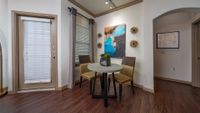 Chic dining nook with modern artwork, featuring a round table and stylish chairs on elegant hardwood floors.