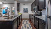 Modern kitchen with sleek granite countertops and stainless steel appliances, enhanced by chic dark cabinetry and elegant decor.