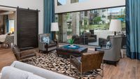 Chic modern living room with floor-to-ceiling windows, stylish furniture, and a view of a vibrant outdoor space.