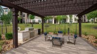 Charming outdoor seating area with a pergola and built-in grill, set in a lush garden courtyard.
