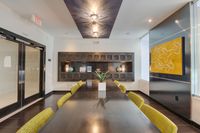 Clubhouse room with long dining table, yellow chairs, and wall shelving