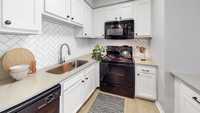 Kitchen, hardwood flooring, black stove, black built in microwave, white cabinetry, white  tile backsplash, under mount sink with gooseneck faucet