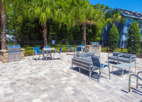 Pool griling area with grill, gray cushioned patio furniture, blue chairs and gray tables