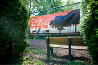 Inviting Summit Unleashed sign on a fenced area with lush greenery, offering a vibrant community space for pet owners.