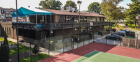 Charming apartment complex with sleek modern design, featuring a vibrant outdoor tennis court and lush green surroundings for an active lifestyle.