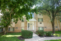 Charming apartment building facade surrounded by lush greenery, featuring a welcoming entrance and well-maintained landscaping.