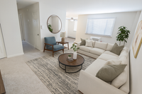 Inviting living room featuring a cozy L-shaped sofa, elegant round coffee table, and chic blue accent chair. Bright, airy space with large window and stylish decor.
