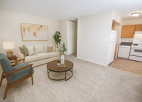 Modern living room with cozy seating, contemporary art, and a view into a fully-equipped kitchen, offering a welcoming and functional space.