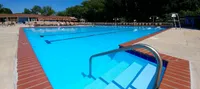 Inviting outdoor swimming pool with crystal-clear water, surrounded by sun loungers and lush greenery, perfect for relaxation and leisure.