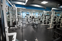 Spacious and modern gym with state-of-the-art equipment, mirrored walls, and sleek lighting, ideal for a complete workout experience.