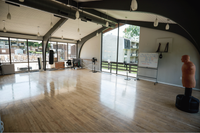Spacious and modern fitness room with large windows offering plenty of natural light, featuring polished hardwood floors and equipped with punching bags, perfect for a well-rounded workout experience.