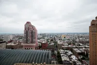 Breathtaking panoramic cityscape view featuring a red high-rise building and elegant architecture under a cloudy sky.