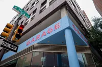 Modern urban building corner featuring a bold blue garage entrance with street signs and a traffic light, symbolizing city convenience.
