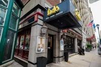 Charming urban pub exterior with inviting signage for food, drink, and banter in a vibrant city setting.