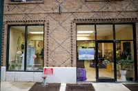Charming brick storefront featuring large windows, organic cleaning services, and stylish potted plants, inviting a refreshing urban experience.