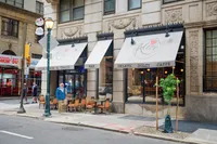Charming Italian cafe exterior with inviting outdoor seating, featuring stylish awnings and elegant architectural details.