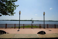 Scenic riverside promenade with elegant lampposts and lush greenery under a clear blue sky.