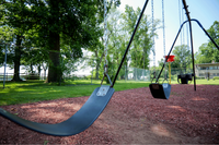 Inviting playground swing set surrounded by lush greenery and vibrant summer trees.