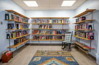 Charming and cozy reading nook featuring wall-mounted shelves filled with colorful books, a cushioned rocking chair, and a vibrant patterned rug.