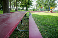 Charming park with vibrant playground, a long picnic table, and lush green surroundings perfect for outdoor relaxation and family fun.