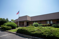 Charming brick building with a well-maintained lawn and an American flag, perfect for community gatherings.