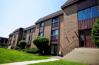 Charming brick apartment complex with lush green landscaping and inviting entrance in a peaceful neighborhood.
