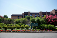 Charming apartment complex at Delaire Landing with lush greenery, vibrant flower beds, and a welcoming sign, offering a serene and inviting atmosphere.