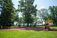 Charming playground nestled in a lush green park, featuring swings and a spiral slide under the shade of majestic trees.