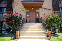 Charming apartment entrance with vibrant pink blossoms accenting the pathway, creating a welcoming and colorful ambiance.