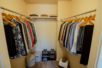 Elegant and organized walk-in closet featuring neatly hung clothes, ample shelf space, and stylish shoe storage.