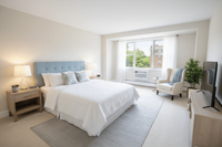 Bright and inviting bedroom with a plush king-sized bed, stylish furnishings, and large window letting in ample natural light.