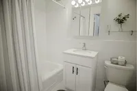 Elegant bathroom with clean white tiles, a sleek vanity, and modern lighting, offering a fresh and inviting atmosphere.