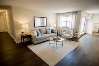 Inviting living room with elegant sofa, modern armchair, and coffee table, highlighted by warm lighting and hardwood floors.