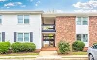 Charming brick and siding apartment building with manicured shrubs and spacious entry in a serene neighborhood setting.